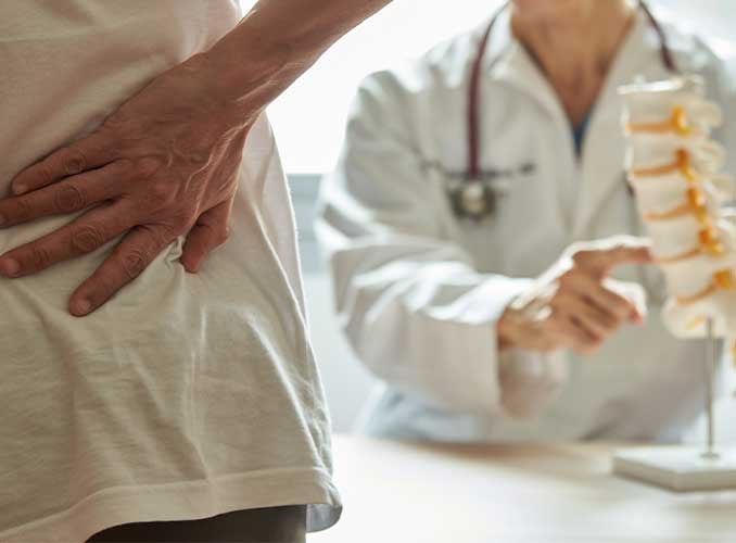physician diagnosing cause of back pain to patient